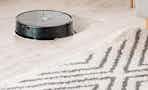 a robot vacuum on a floor next to a rug