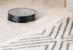a robot vacuum on a floor next to a rug