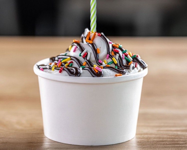 A small ice cream custard from BurgerFi on a table with a candle on top.