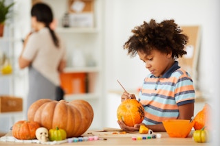 young boy painting pumpkins at home