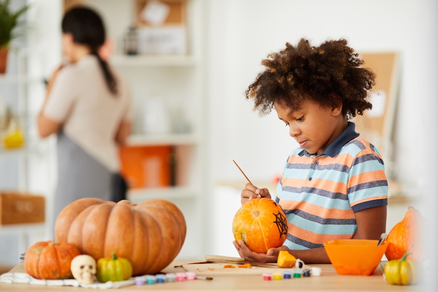 young boy painting pumpkins at home