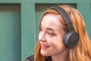 Lifestyle image of a woman wearing a pair of black JBL headphones