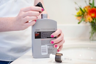 Woman putting a squeeze bottle cap on a pump lotion bottle.