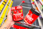 person holding six star pre workout over a cart with protein powder in it