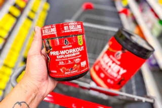 person holding six star pre workout over a cart with protein powder in it