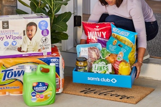 a person at their front door, picking up a sam's club same day delivery order from the welcome mat