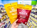 hand holding up two bags of halls cough drops at walgreens