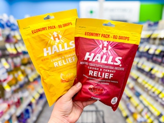 hand holding up two bags of halls cough drops at walgreens