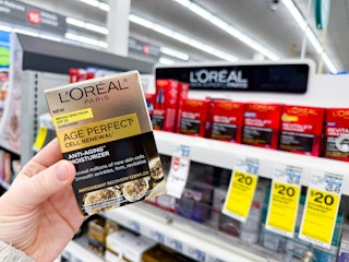 person holding loreal moisturizer in front of the loreal display