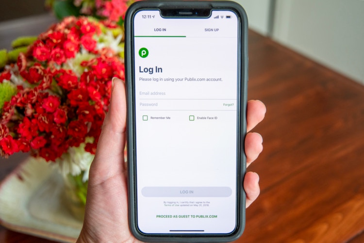 Hand holding a phone showing how to log in to Publix or create an account in the free Publix app.