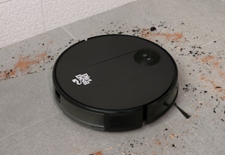 black Dirt Devil robot vacuum cleaning up debris