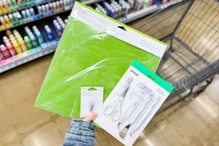 person holding cricut cutting mats and tools over a cart