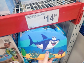 hand holding a kids body glove life jacket floatie with a shark on it