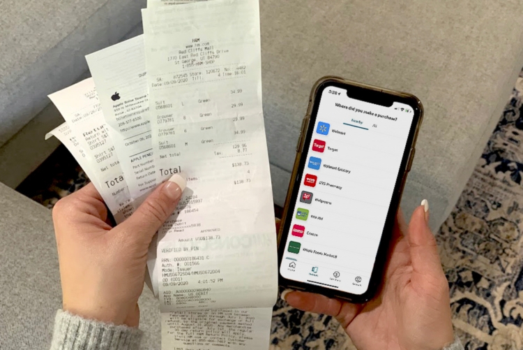 Someone using their iphone with ibotta to save and get cash back with paper receipts