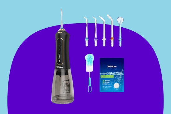 A black water dental flosser with a clear water tank has five extra tips, a cleaning brush, and cleaning tablets.