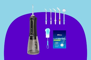 A black water dental flosser with a clear water tank has five extra tips, a cleaning brush, and cleaning tablets.