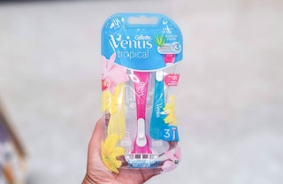hand holding pack of Gillette Venus Tropical disposable razors in aisle