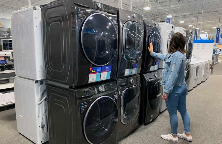 A person looking at washing machines and dryers at Best Buy