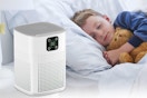 a boy sleeping next to an air purifier