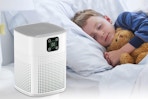 a boy sleeping next to an air purifier