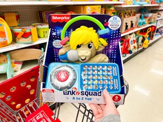 hand holding a fisher-price links squad toy in front of target shelves