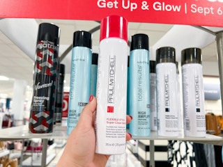 someone holding a dry shampoo by a display of them