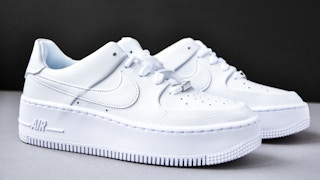 White nike shoes on a grey table behind a dark background