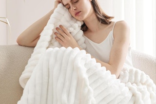 woman sitting on couch with blanket over them