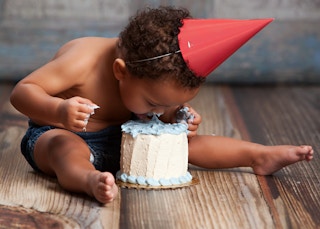 A baby sticking his face into a small birthday cake