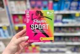      a hand holding playtex sport tampons in a store aisle
