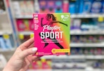 a hand holding playtex sport tampons in a store aisle