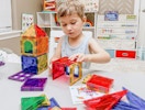 a little kid playing with magnetic tiles in a playroom
