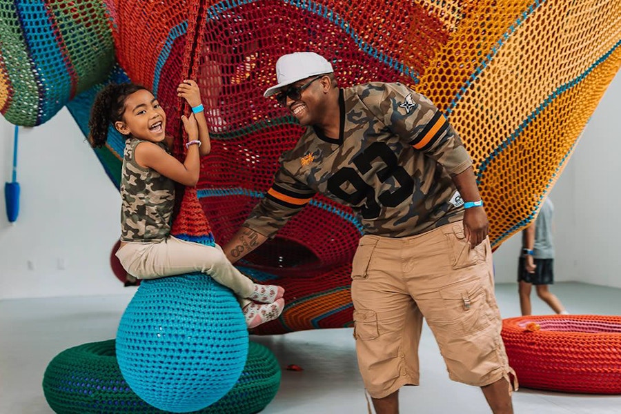 A dad pushing his child on an interactive museum exhibit