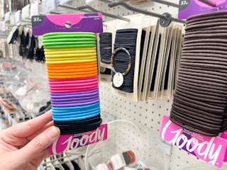 a person holding rainbow colored Goody hair elastics