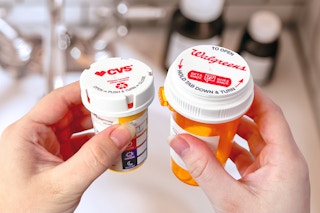 someone holding two prescription bottles, one from CVS and one from Walgreens