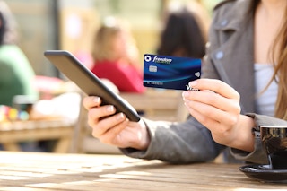 Woman holding a bank card while holding a phone
