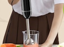 a person blending a smoothie with an immersion blender