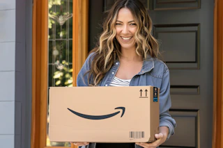 a woman standing in a doorway holding an amazon box