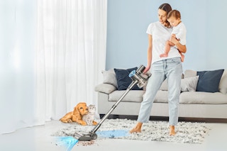 Lifestyle image of Tasvac Stick Vacuum being used by a woman holding her baby in her living room