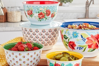 Five different sized melamine bowls with flower graphics on the outside and bright solid colors inside, plus clear lids