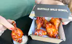 a person dipping wings in ranch