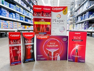 A variety of Colgate products sitting on a store floor in the middle of a store aisle.