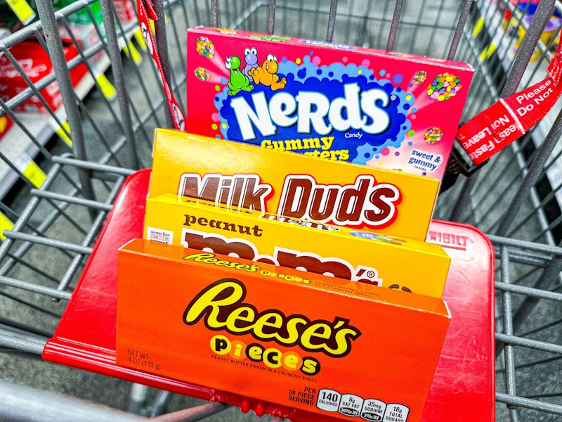 nerds, milk duds, m&ms, and reeses pieces candy boxes in a cart