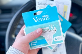 hand holding venus smooth razor refills with a walgreens receipt in a car