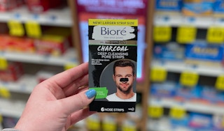 A hand holding Biore pore strips in a store aisle.