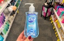 A hand holding a bottle of Dial liquid hand soap in a store aisle.