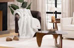 a white fur blanket on a chair in a living room