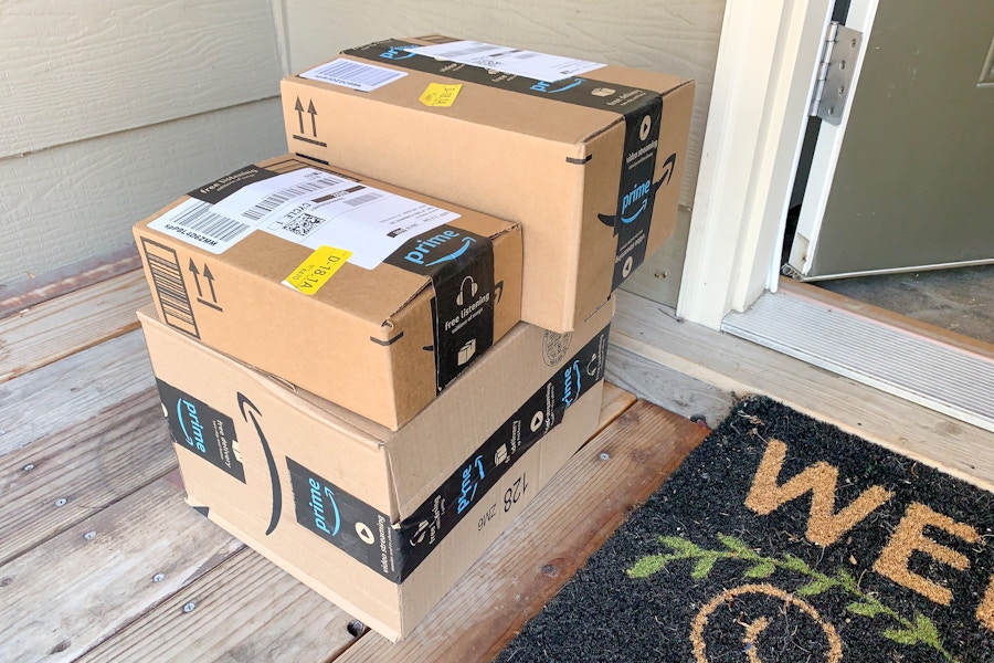 Three amazon prime boxes of varying sizes stacked on someone's doorstep