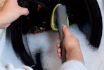 person using dishwand to scrub a plate
