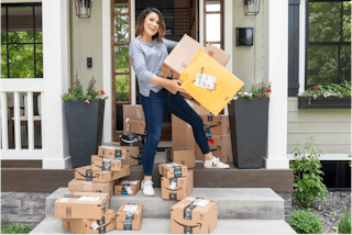 joanie holding amazon boxes on a porch
